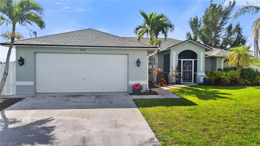 Ranch-style house with a front yard, concrete driveway, stucco siding, and a shingled roof