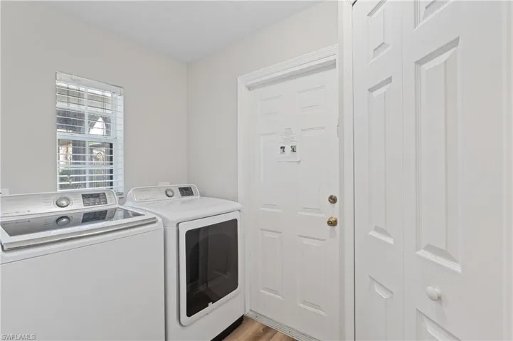Clothes washing area featuring light wood finished floors, washer and clothes dryer, and laundry area