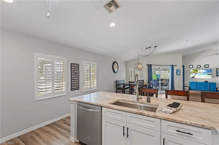 Kitchen featuring stainless steel dishwasher, visible vents, a sink, and vaulted ceiling