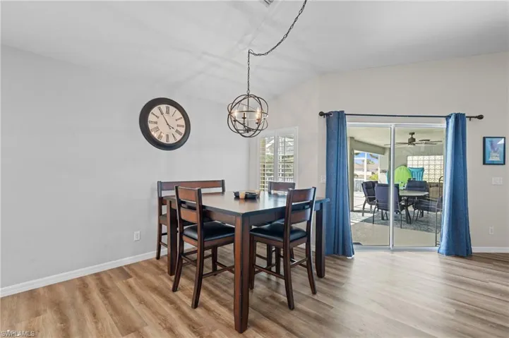 Dining space with baseboards, lofted ceiling, wood finished floors, and an inviting chandelier