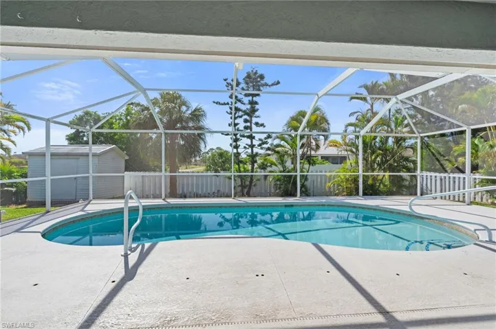 Outdoor pool with fence, a lanai, a patio, an outbuilding, and a shed