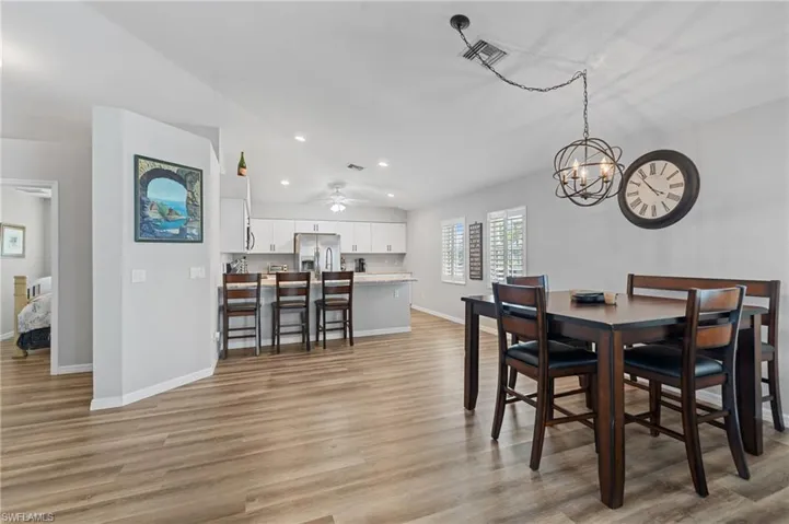 Dining space with light wood-type flooring, baseboards, lofted ceiling, and visible vents