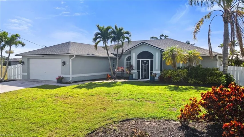 Ranch-style house with concrete driveway, stucco siding, fence, an attached garage, and a front lawn