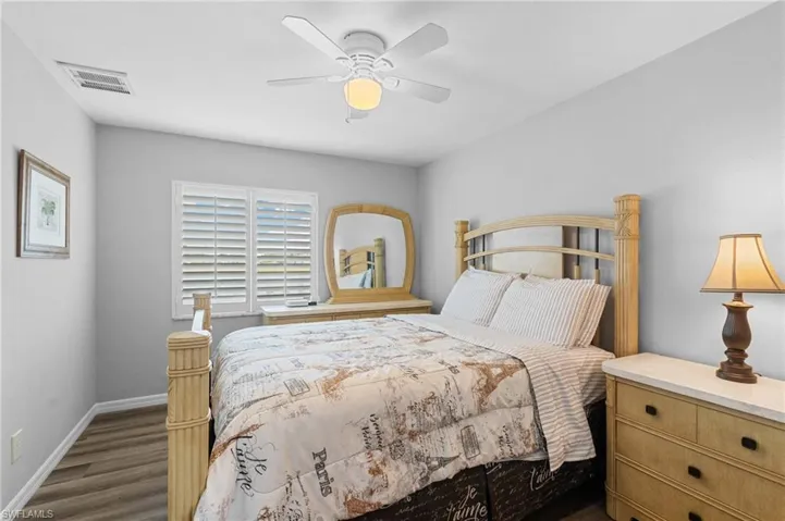 Bedroom with baseboards, dark wood-style flooring, ceiling fan, and visible vents