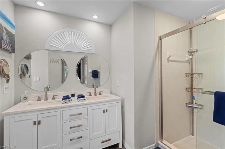 Bathroom with double vanity, a sink, recessed lighting, and a shower stall