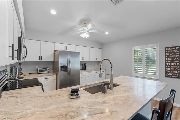 Kitchen featuring visible vents, a kitchen bar, a ceiling fan, appliances with stainless steel finishes, and a sink