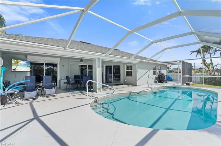 Outdoor pool featuring glass enclosure, fence, ceiling fan, and a patio area