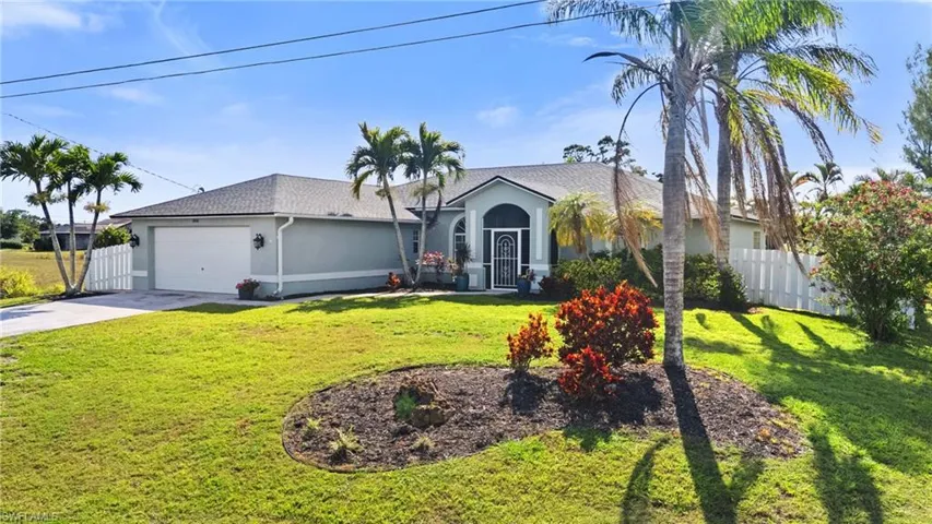 Ranch-style home featuring a front yard, concrete driveway, stucco siding, fence, and an attached garage
