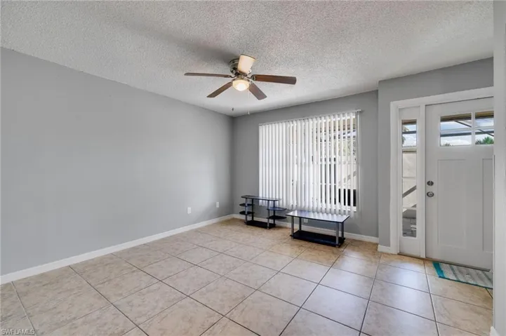 Entrance foyer with a textured ceiling, light tile patterned floors, and ceiling fan