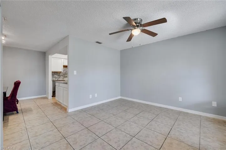 Unfurnished room featuring a textured ceiling, a ceiling fan, and light tile patterned flooring