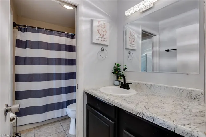 Bathroom featuring curtained shower, vanity, and light tile patterned floors