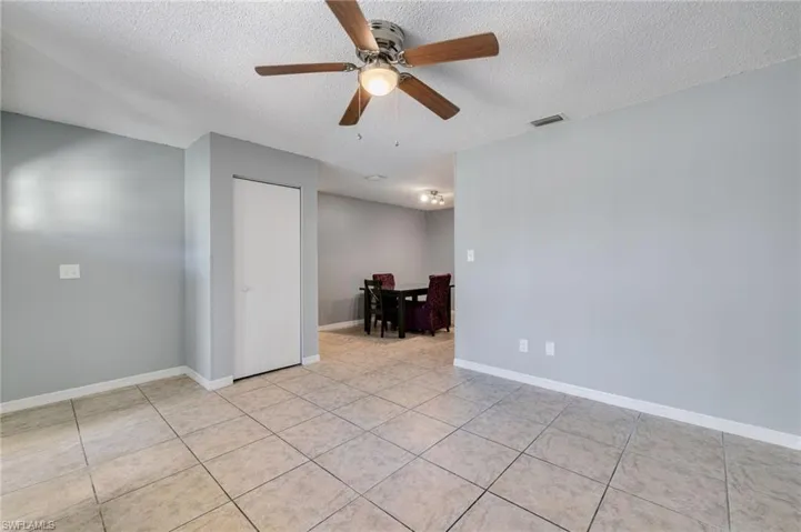 Unfurnished room with a textured ceiling, ceiling fan, and light tile patterned floors