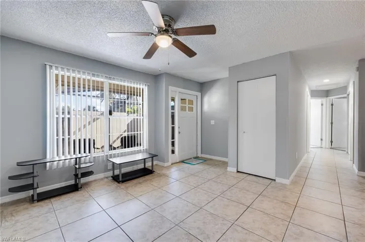 Foyer entrance featuring a textured ceiling, light tile patterned floors, and ceiling fan