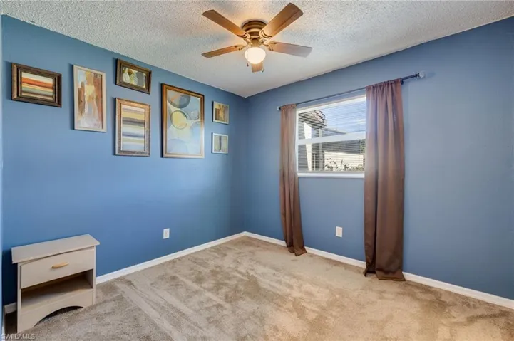 Unfurnished room featuring light carpet, a textured ceiling, and ceiling fan