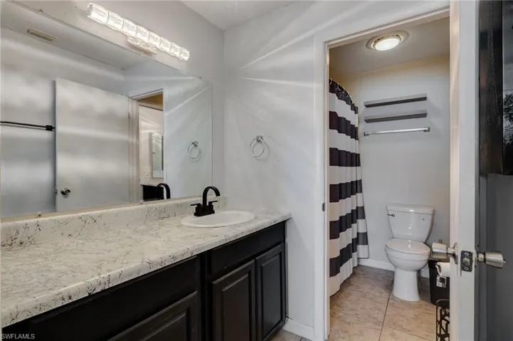 Bathroom with curtained shower, vanity, and light tile patterned floors