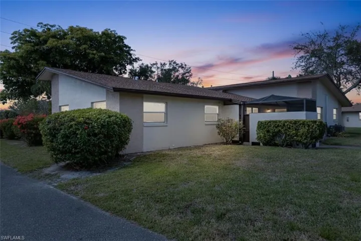 Property exterior at dusk with a lawn and stucco siding