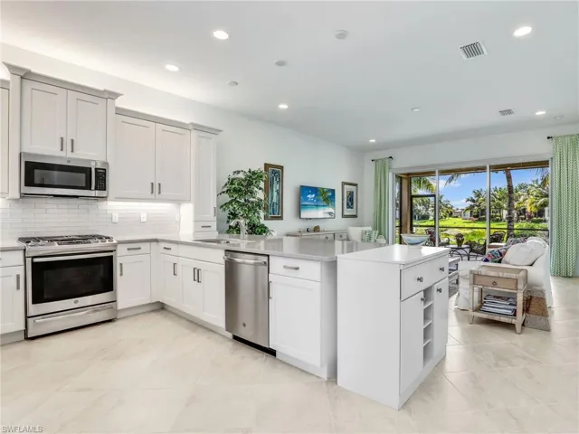 Kitchen featuring backsplash, sink, light tile flooring, and appliances with stainless steel finishes