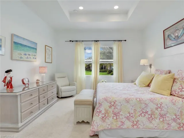 Bedroom with a raised ceiling and light colored carpet