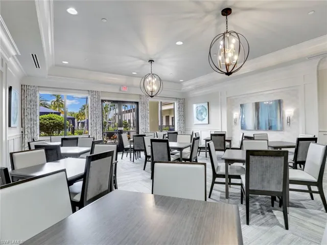 Dining space featuring a notable chandelier, light parquet flooring, ornamental molding, and a raised ceiling