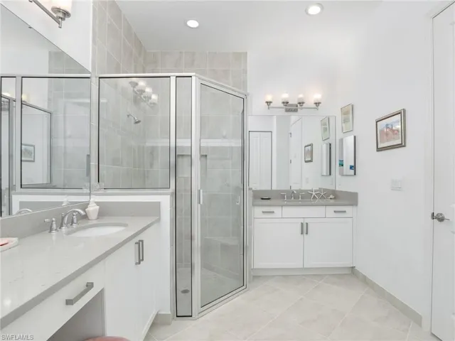 Bathroom with vanity with extensive cabinet space, tile flooring, and a shower with door