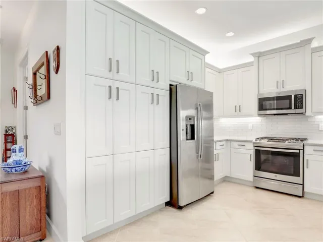 Kitchen featuring light tile floors, backsplash, and appliances with stainless steel finishes