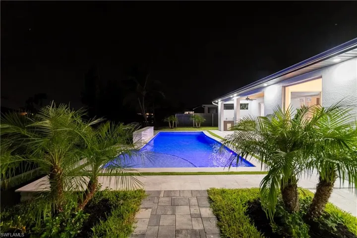 Pool at night with a patio area