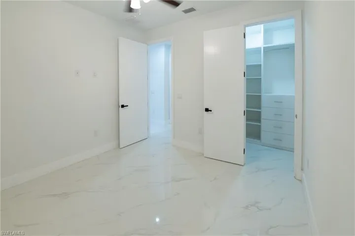 Unfurnished bedroom featuring a walk in closet, a closet, and ceiling fan
