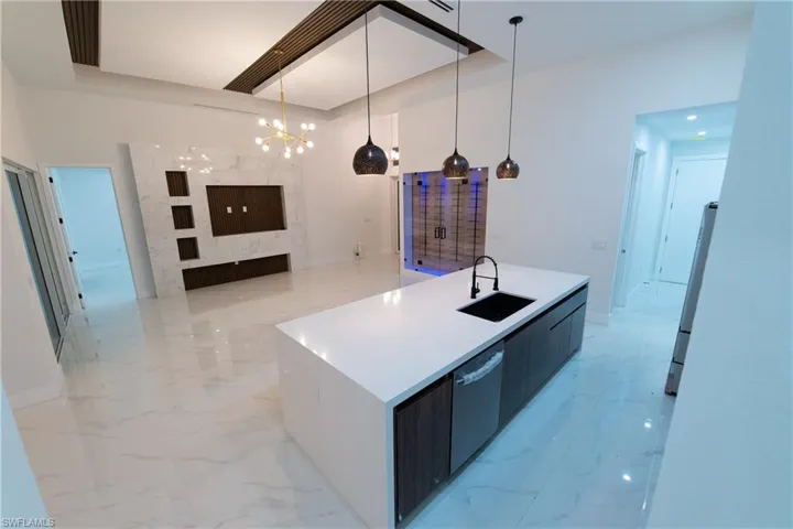 Kitchen with sink, hanging light fixtures, stainless steel dishwasher, an island with sink, and white fridge