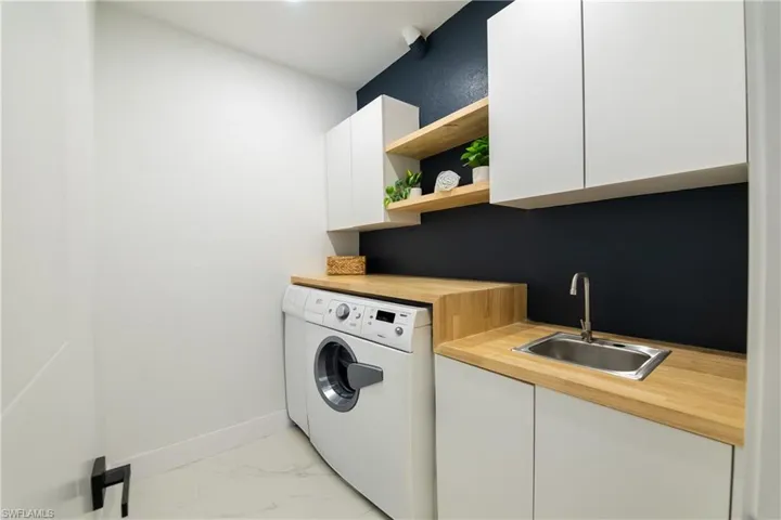 Laundry area with sink, cabinets, and independent washer and dryer