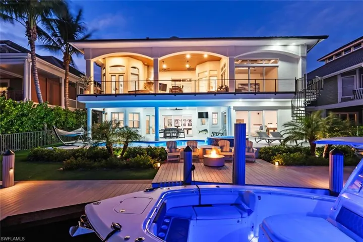 Rear view of house with a balcony, an outdoor fire pit, and stucco siding
