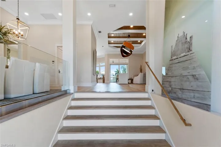 Staircase featuring ornamental molding, wood finished floors, recessed lighting, and a high ceiling