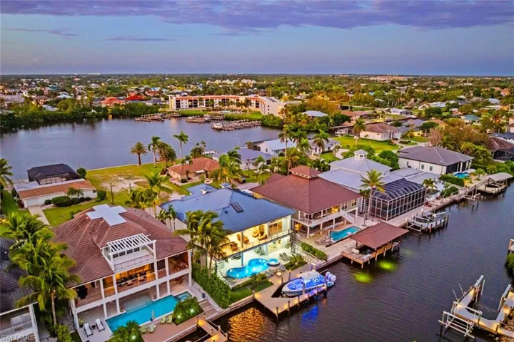 Aerial view at dusk of a water view and view of pool