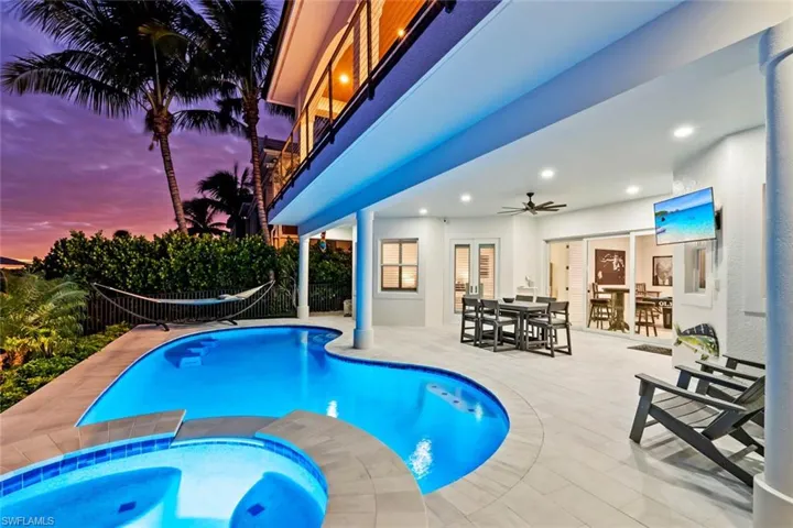 View of swimming pool featuring a balcony, a ceiling fan, a patio, a pool with connected hot tub, and outdoor dining area