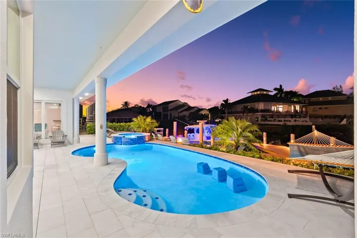 Pool at dusk with a patio and a pool with connected hot tub