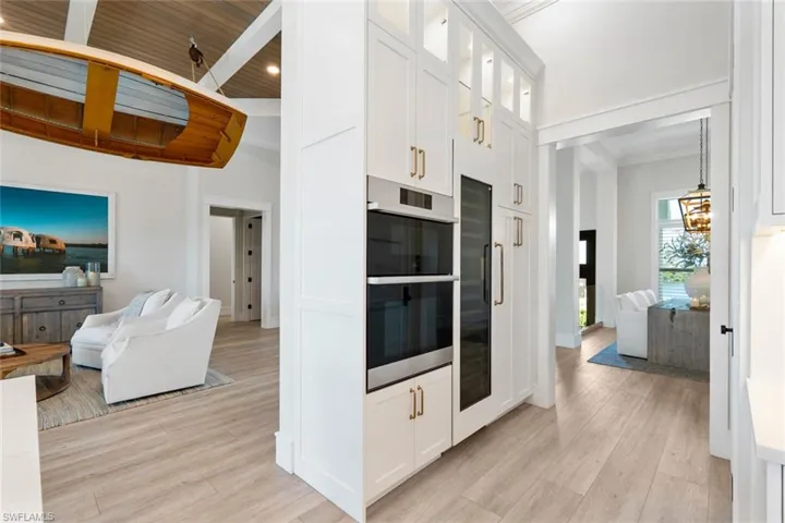 Kitchen featuring glass insert cabinets, double oven, white cabinetry, light wood-style floors, and refrigerator