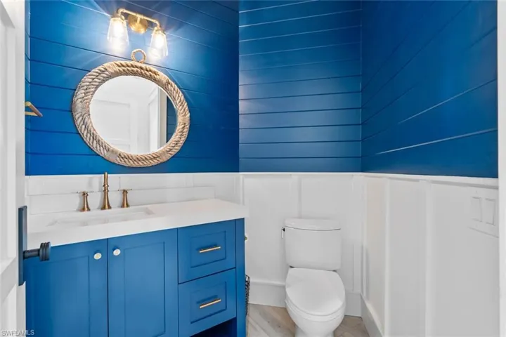 Bathroom featuring vanity, a decorative wall, a wainscoted wall, and light wood finished floors