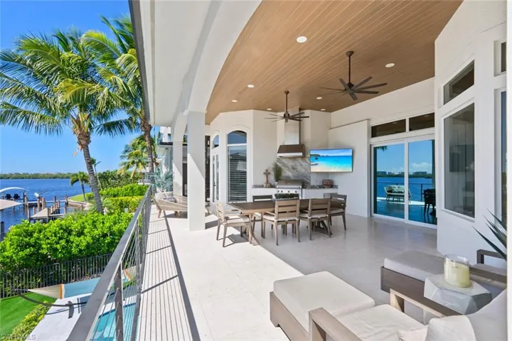 View of patio with outdoor dining space, a water view, a ceiling fan, grilling area, and outdoor lounge area