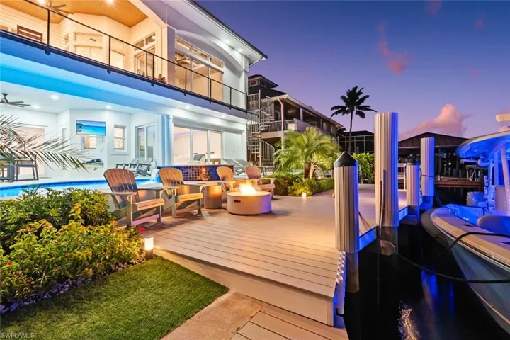 Deck at dusk with a balcony, a fire pit, an outdoor pool, and a patio