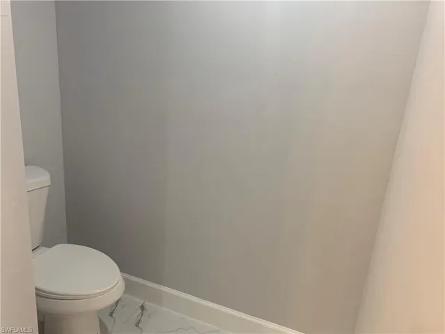 Bathroom with marble look tile flooring and baseboards
