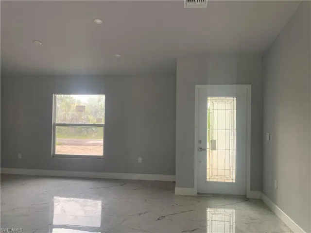 Empty room featuring light marble finish floors and recessed lighting