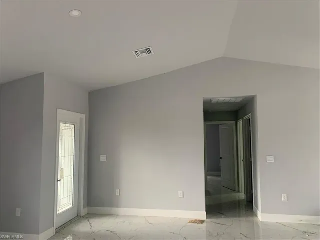 Spare room with light marble finish floors and lofted ceiling
