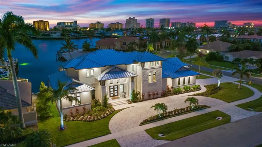 View of front facade featuring a standing seam roof, a metal roof, curved driveway, a skyline view, and a front yard