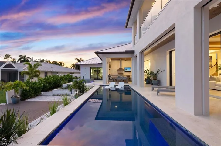 Pool at dusk with an outdoor kitchen, a patio area, and an outdoor pool