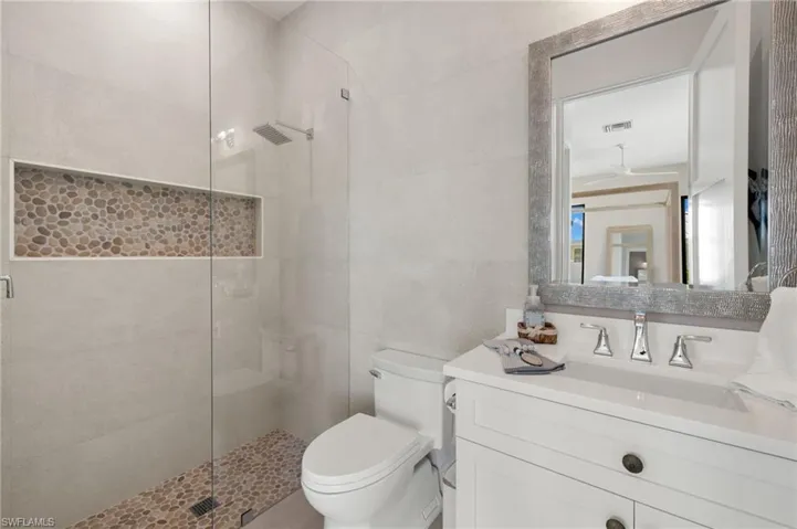 Bathroom featuring a shower stall, vanity, and tile walls