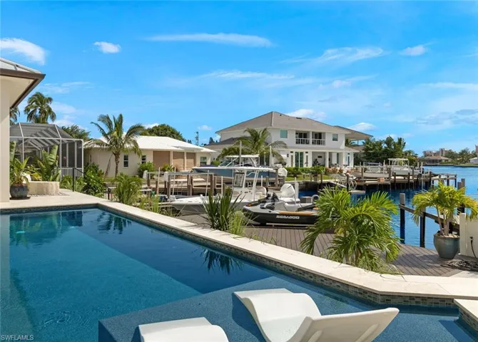 Outdoor pool featuring a boat dock, boat lift, a patio, a sunroom, and a water view