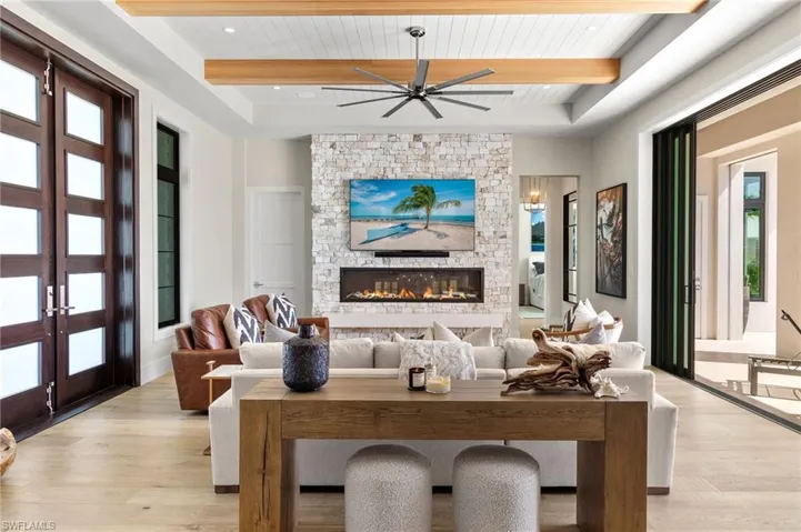 Living room with light wood-style floors, a fireplace, a wood ceiling with exposed beams, and a ceiling fan