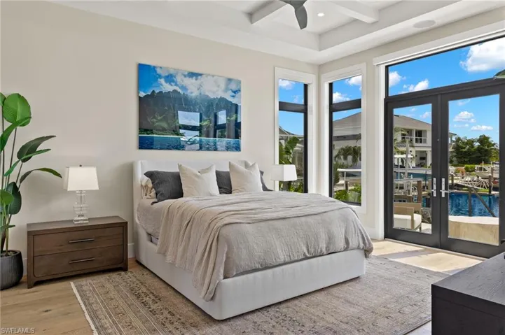 Bedroom with access to exterior, beam ceiling, light wood-type flooring, a water view, and coffered ceiling