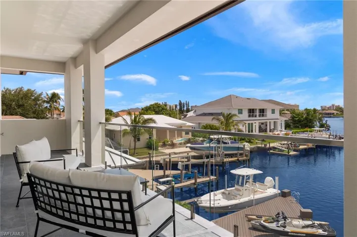 View of patio with a water view, an outdoor living space, and a boat dock