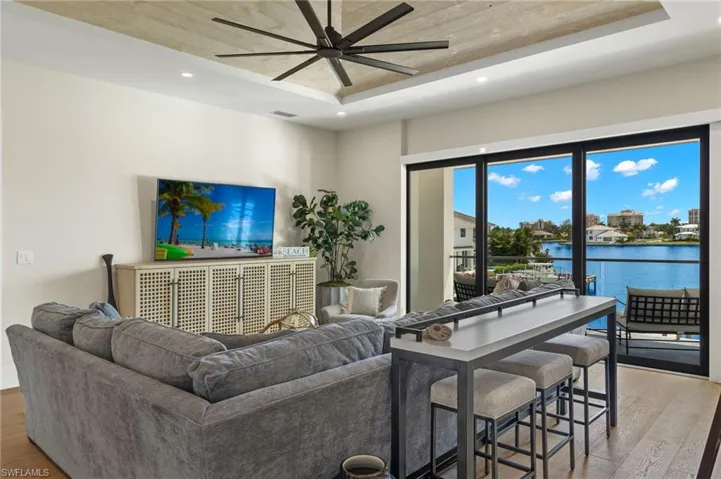 Living area featuring light wood-style flooring, recessed lighting, a tray ceiling, and a ceiling fan