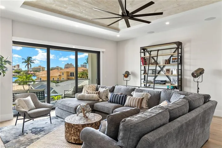 Living room featuring light wood-style flooring, recessed lighting, a tray ceiling, and ceiling fan